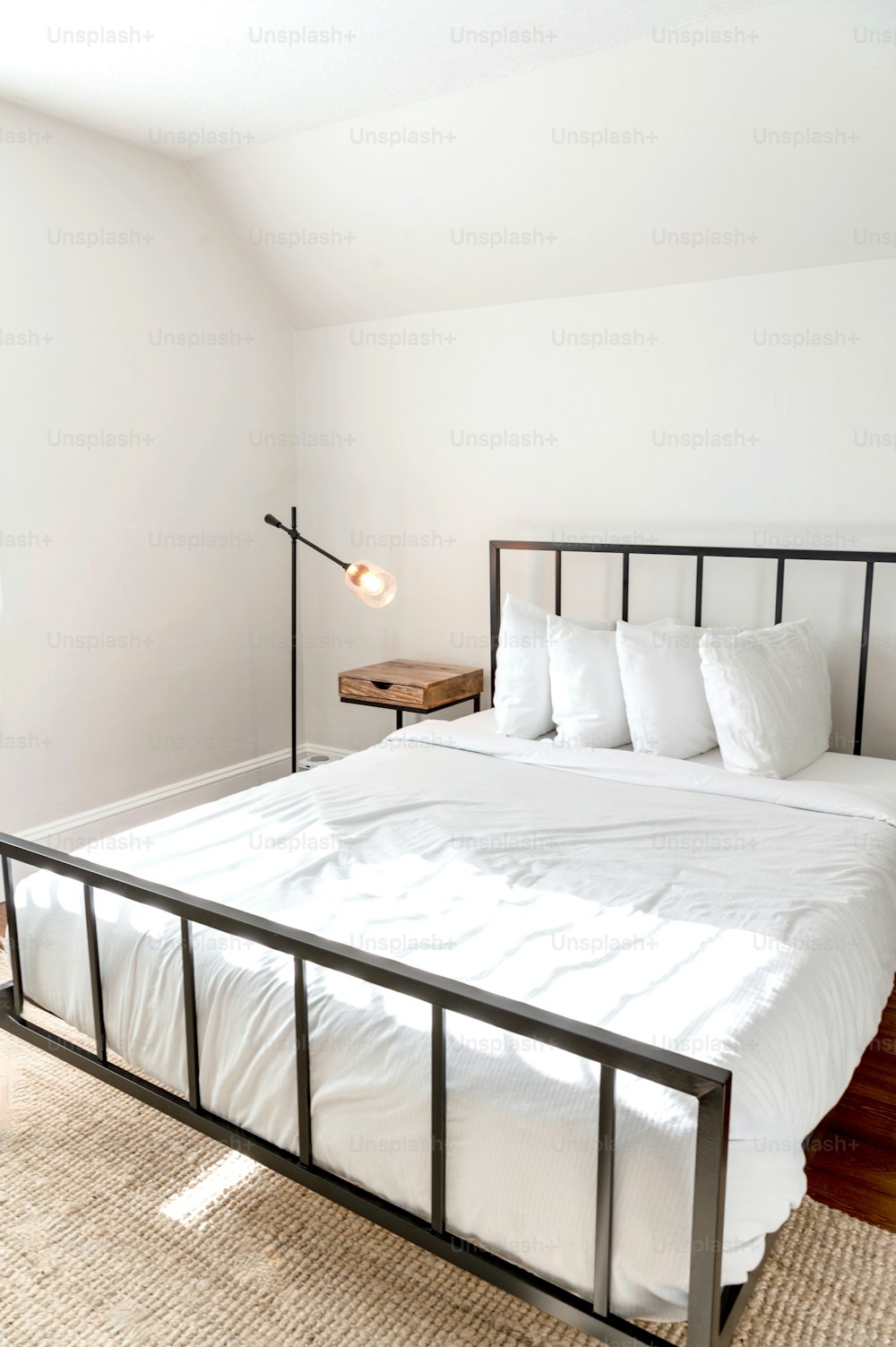 un lit avec des draps blancs et des oreillers dans une chambre