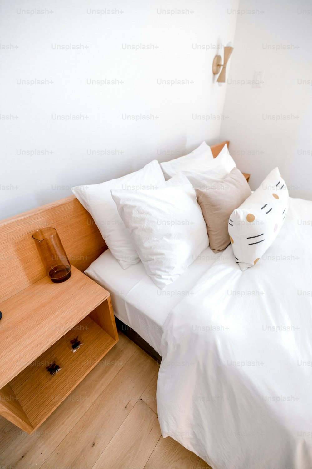 a bed with a white comforter and a wooden night stand