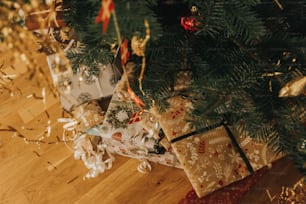 wrapped presents under a christmas tree on a wooden floor