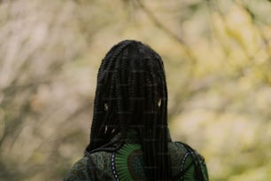 a woman with dreadlocks standing in front of a tree