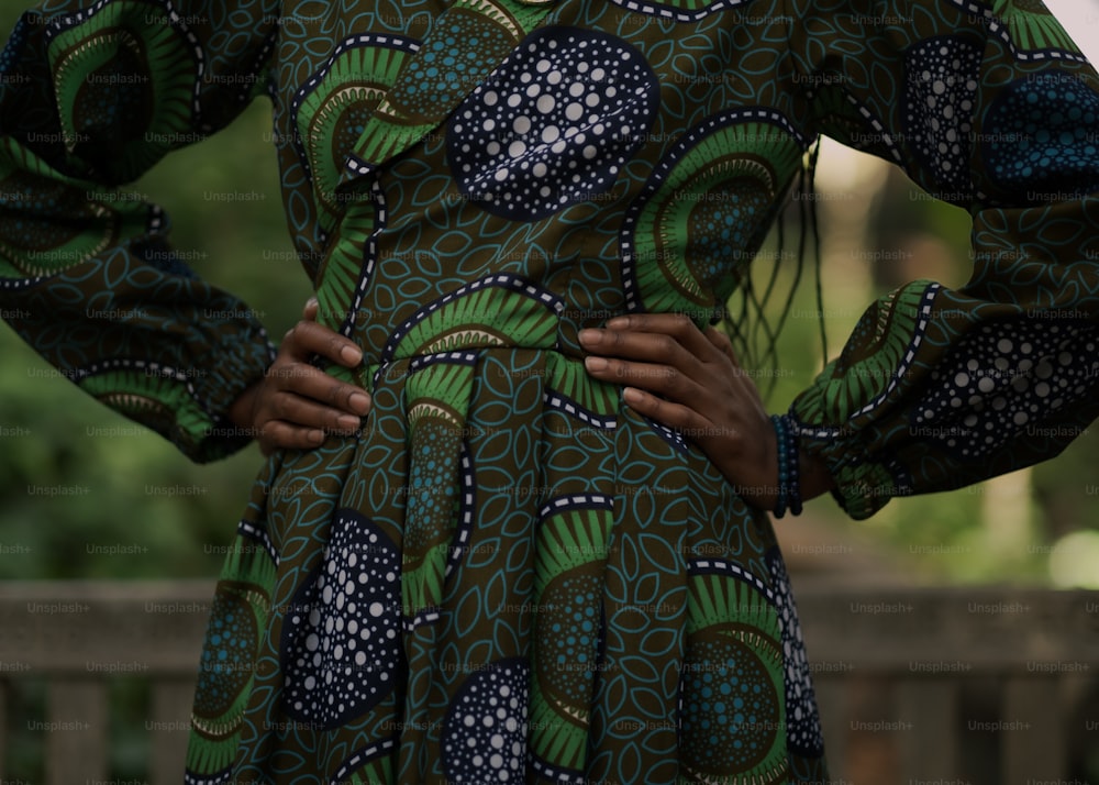 a woman in a green and blue dress with her hands on her hips