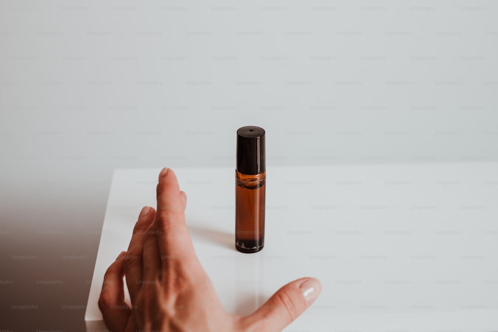 a person's hand reaching for a small bottle of essential oils