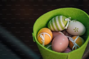 a green bucket filled with different colored eggs