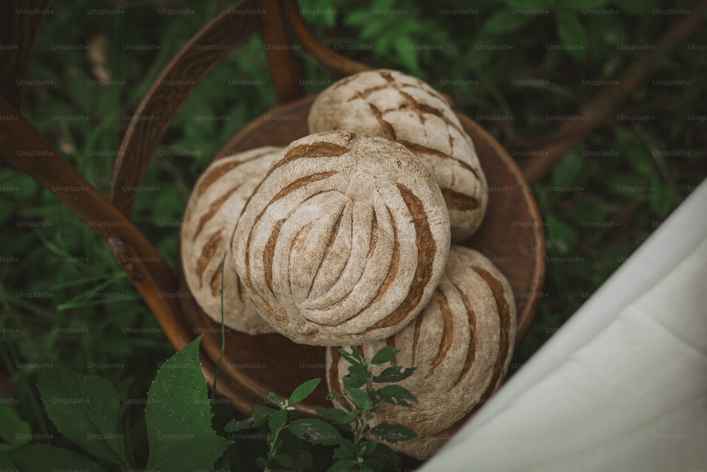 a wooden bowl filled with bread on top of a lush green field