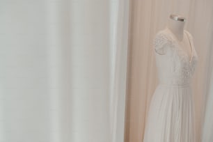 ein weißes Kleid auf einer Schaufensterpuppe vor einem Vorhang