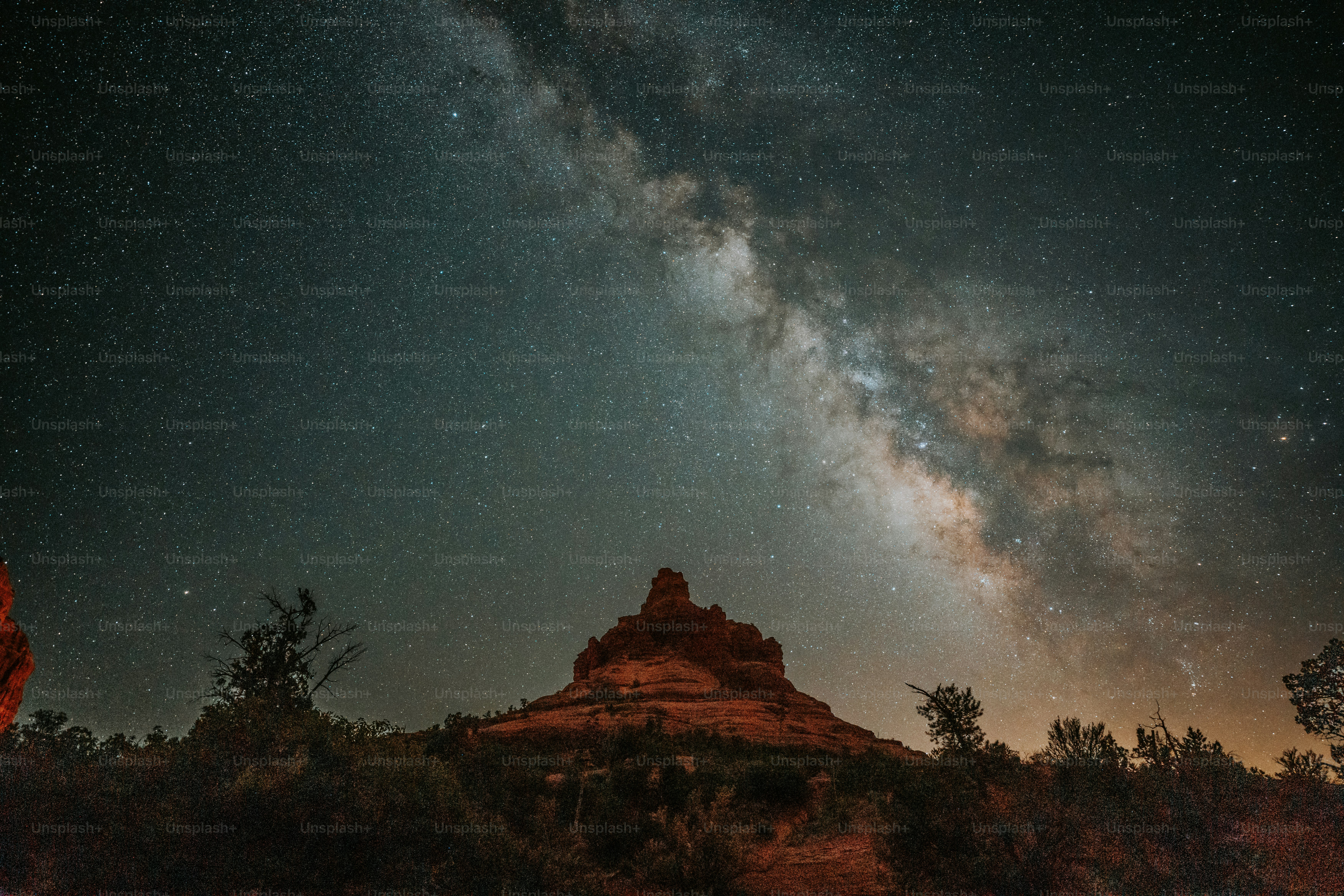 O céu noturno está cheio de estrelas acima de uma montanha