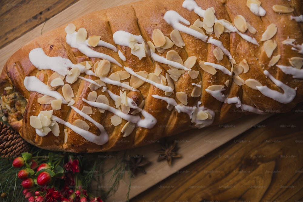 a loaf of bread with almonds and icing on a cutting board