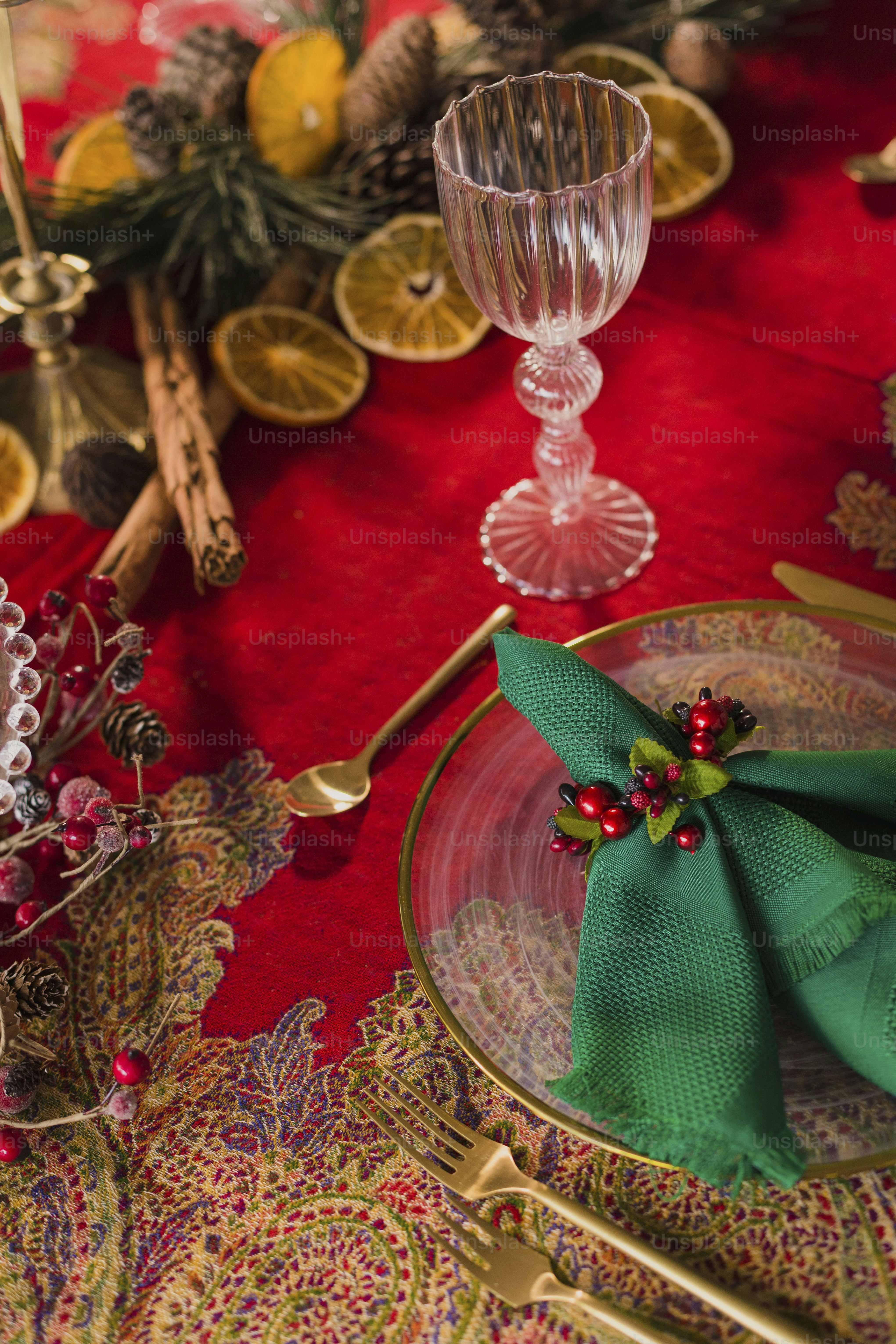 a place setting with a red table cloth and a green napkin