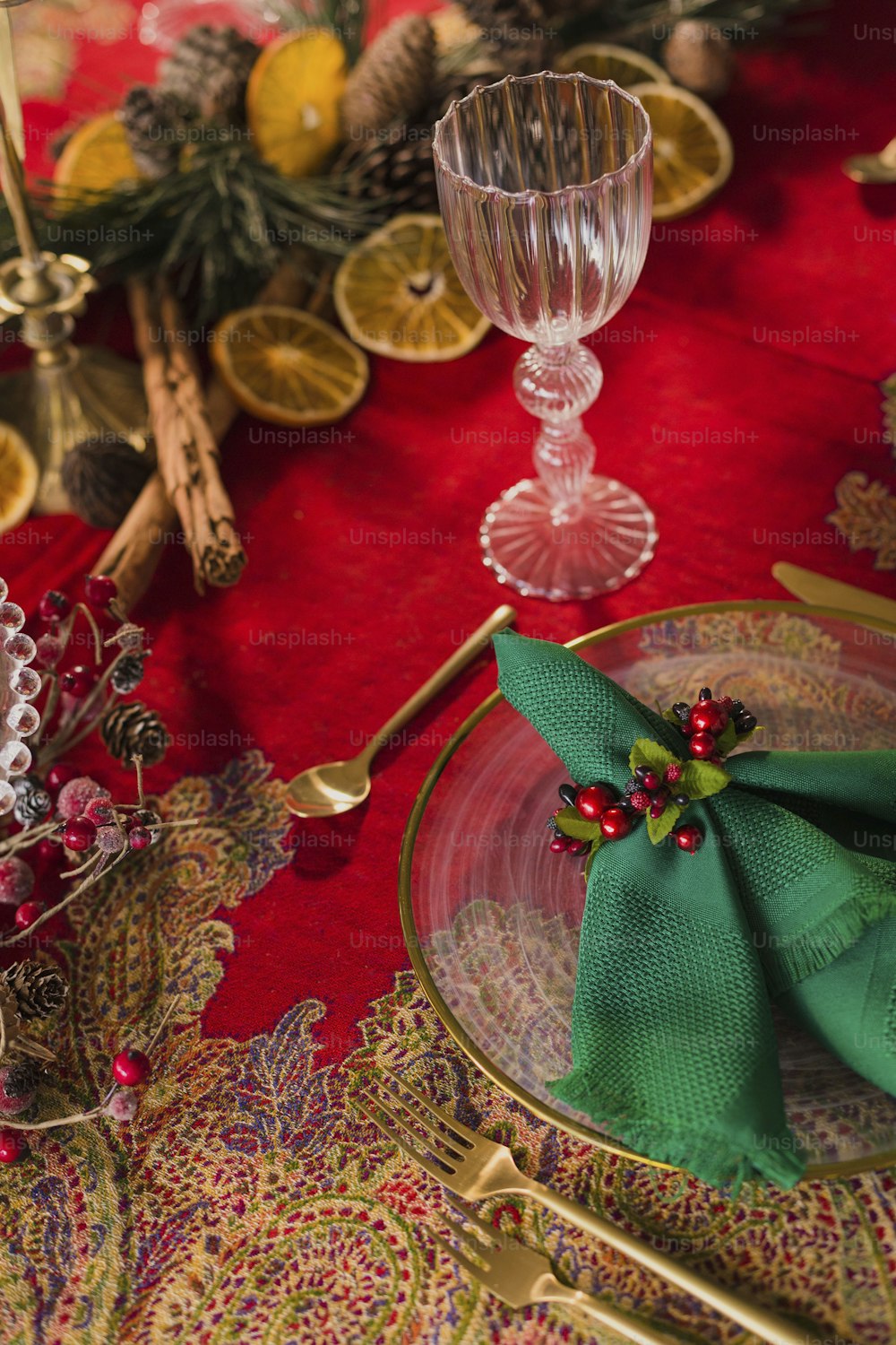 a place setting with a red table cloth and a green napkin