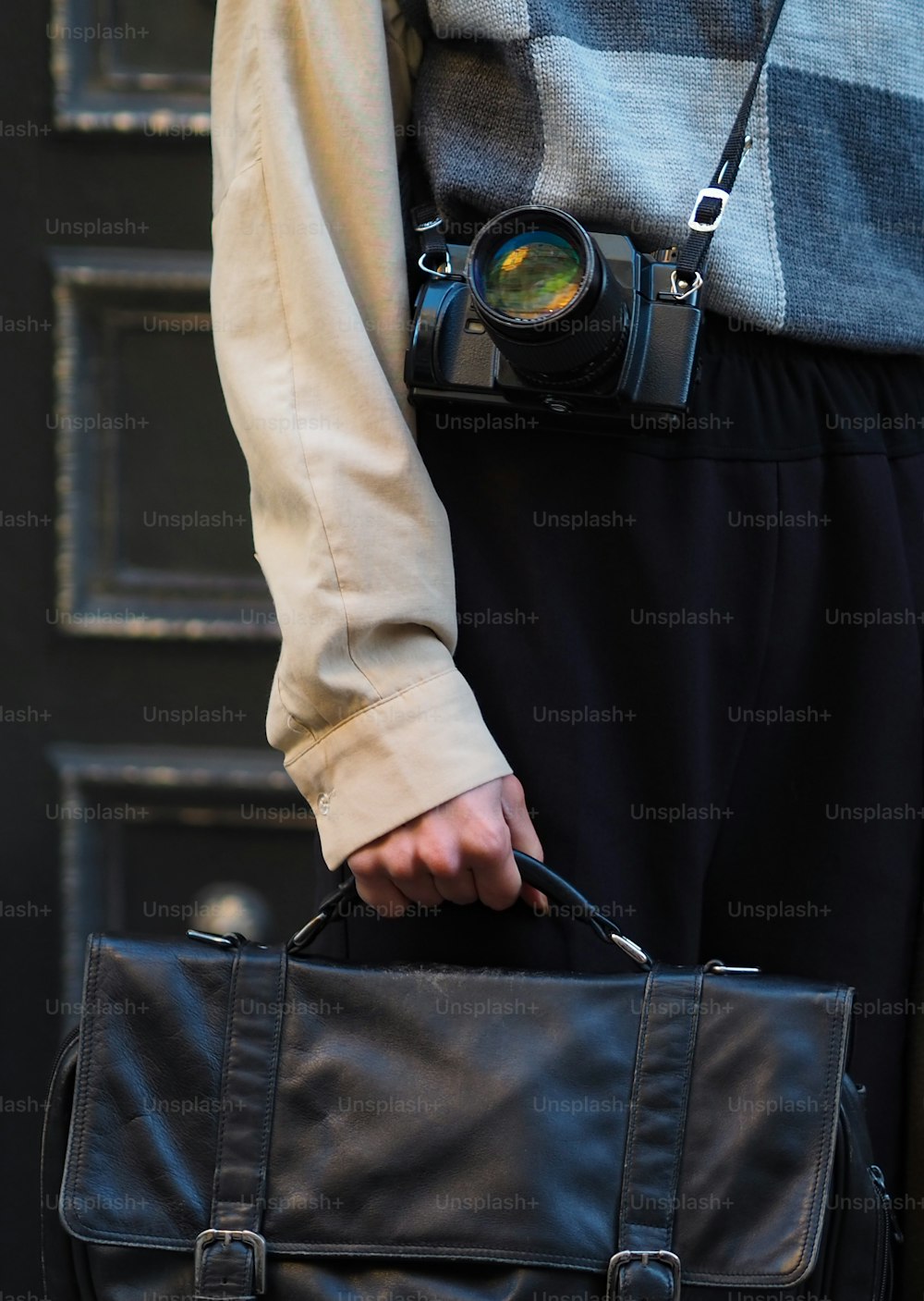 una persona con in mano una borsa nera e una macchina fotografica