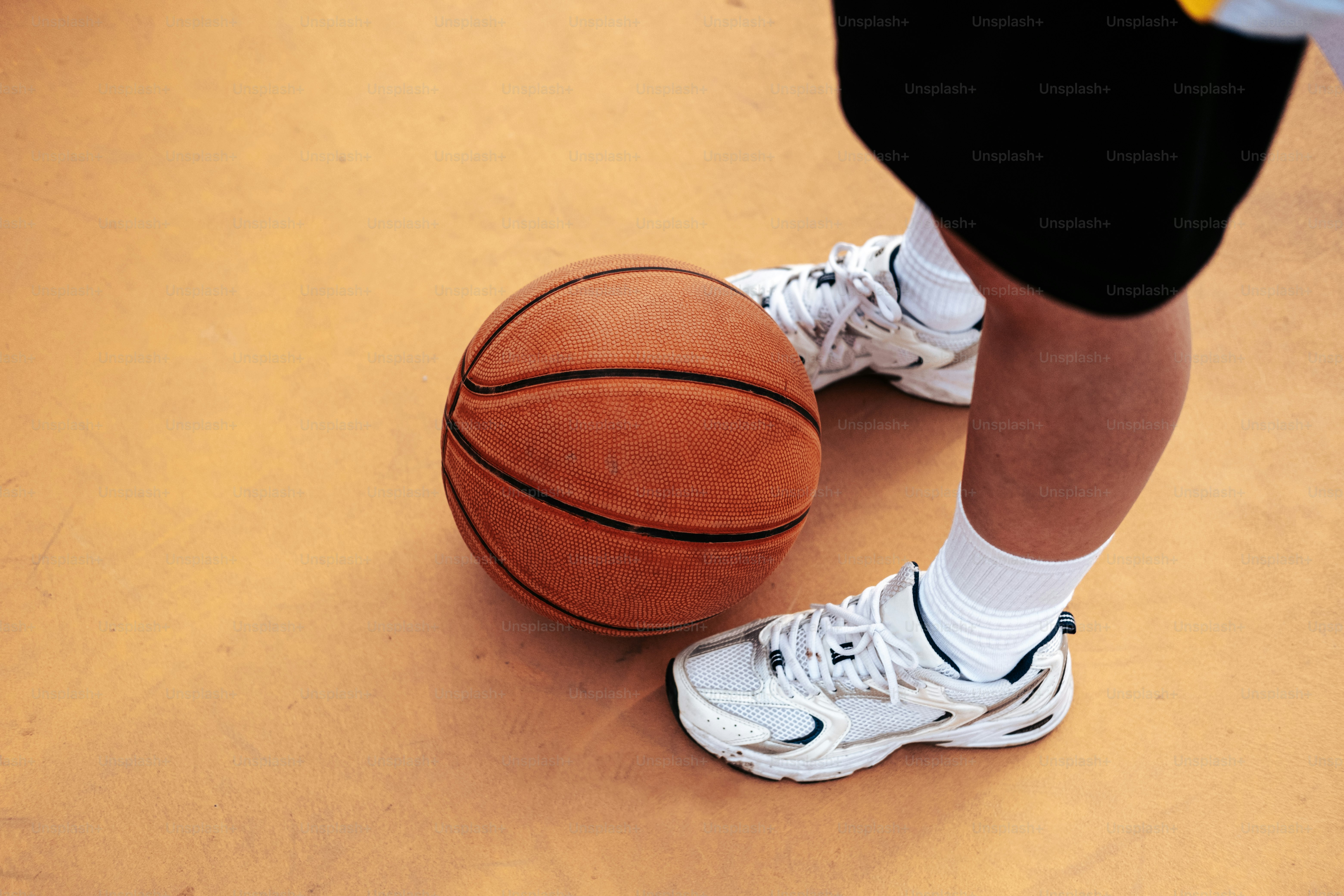seseorang yang berdiri di samping bola basket di lapangan