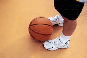 Una persona parada junto a una pelota de baloncesto en una cancha