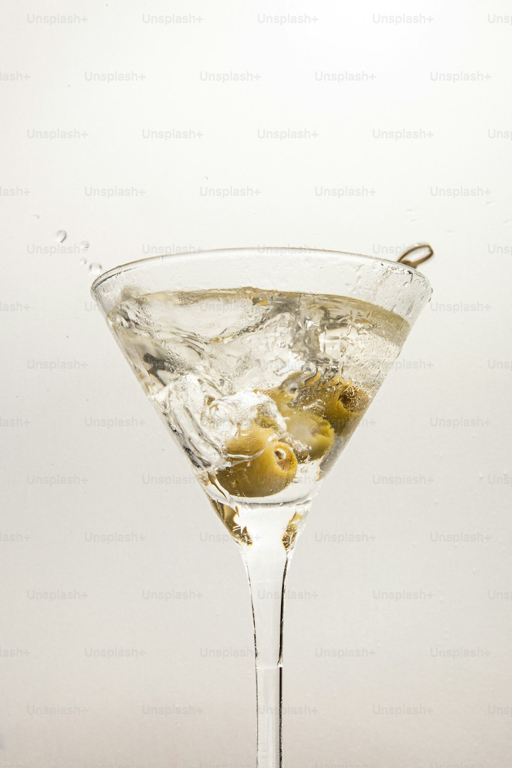 a martini glass filled with ice and olives