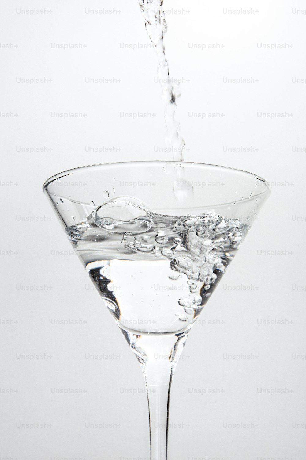 Una copa de martini llena de agua sobre un fondo blanco