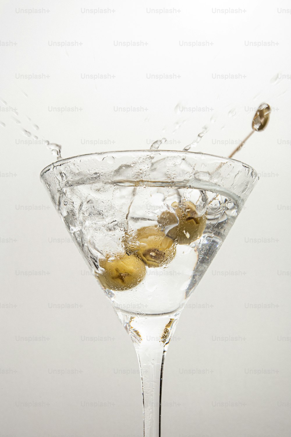 a martini glass filled with water and olives