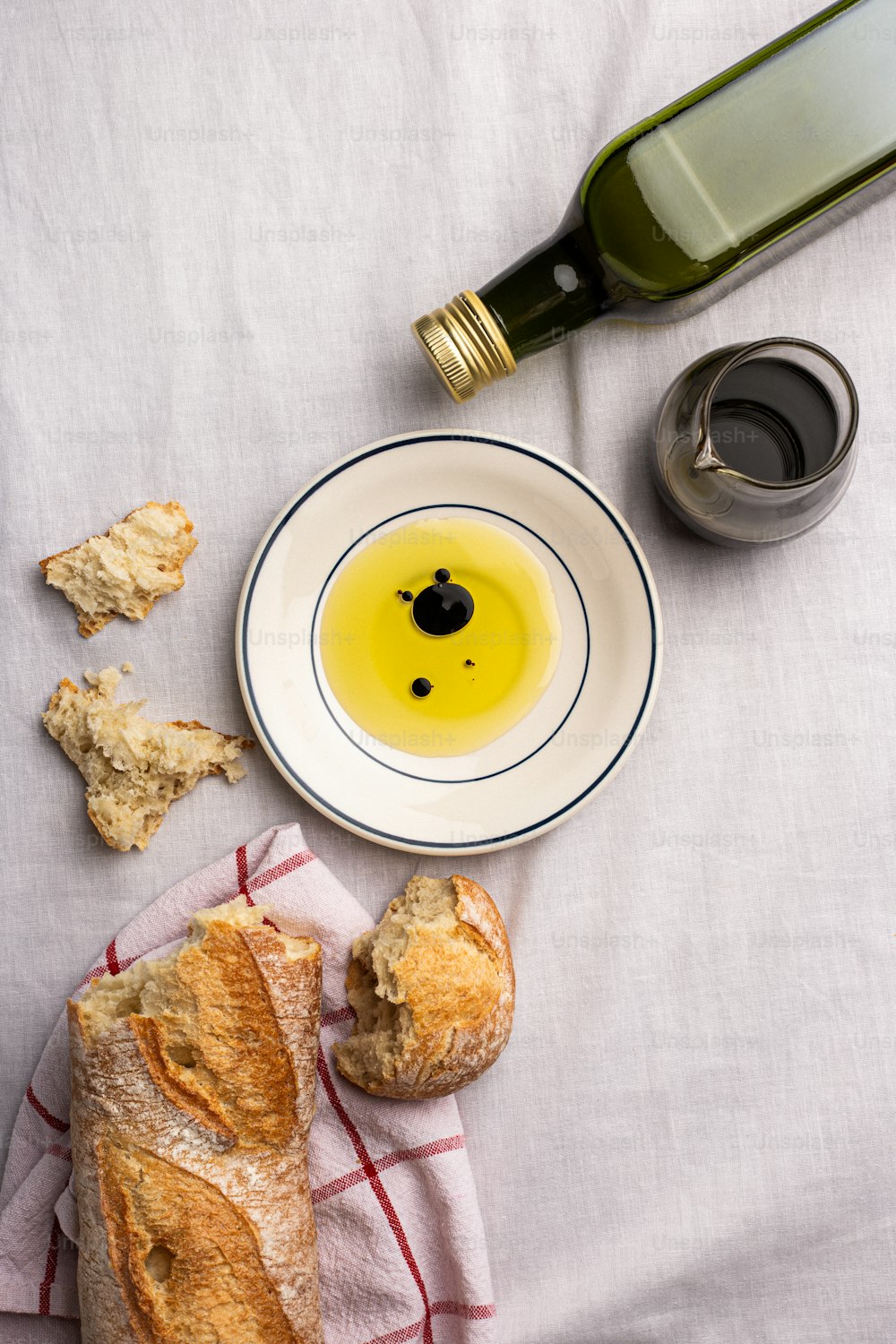 a bowl of olive oil next to a loaf of bread and a bottle of olive