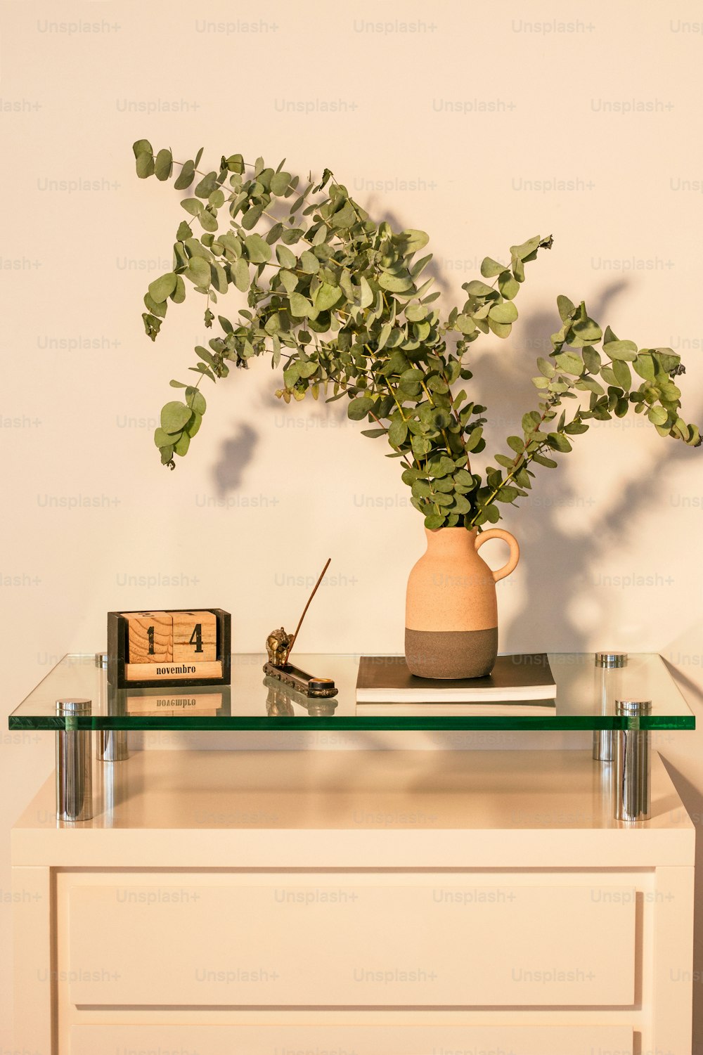 a vase with a plant on a glass table