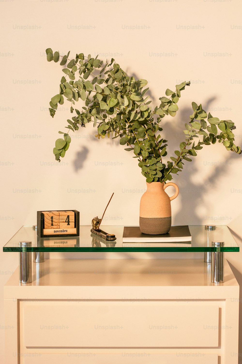 un jarrón con una planta en una mesa de vidrio