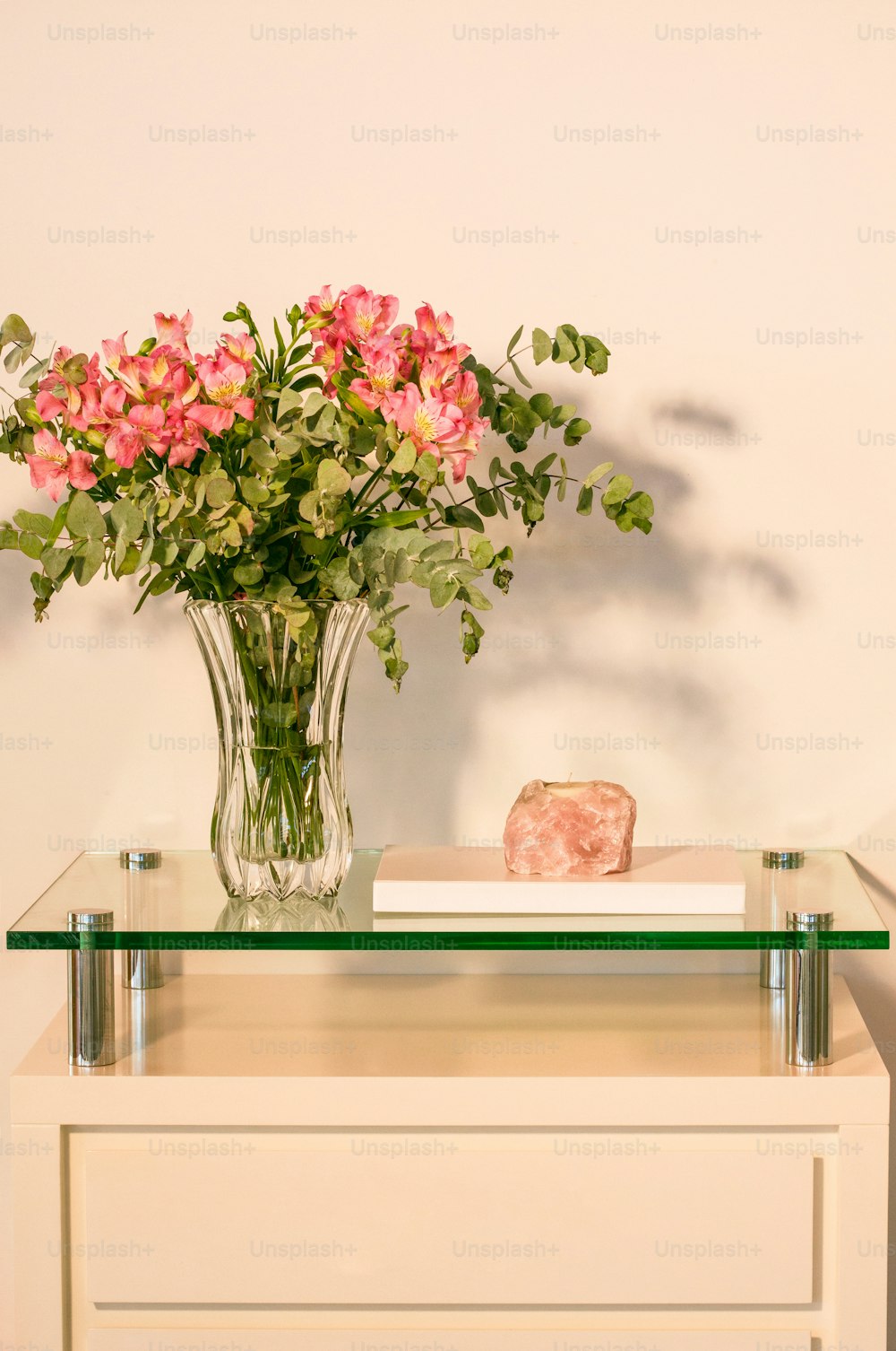 eine Vase mit rosa Blumen, die auf einem Tisch sitzt