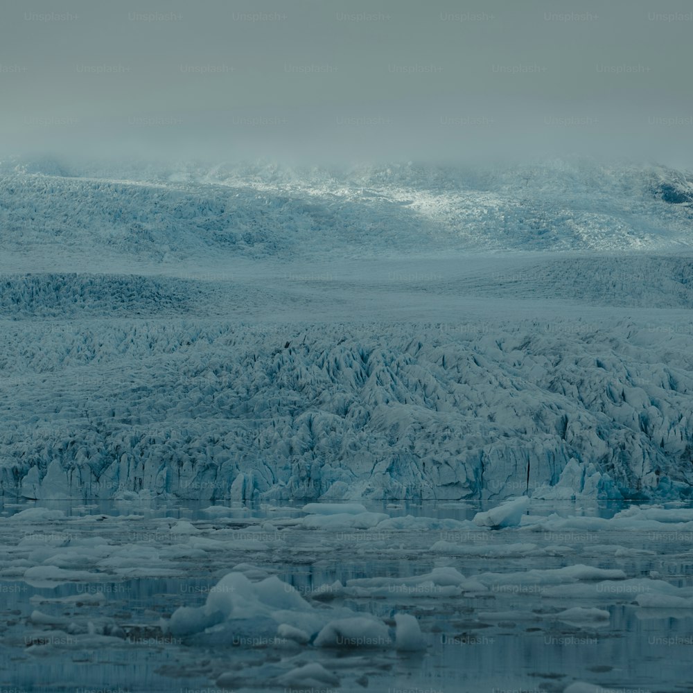 a mountain covered in lots of ice next to a body of water