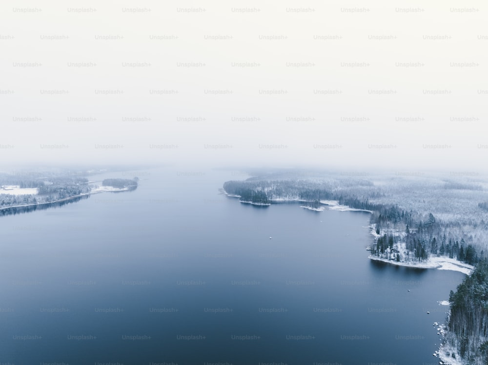 a large body of water surrounded by snow covered trees