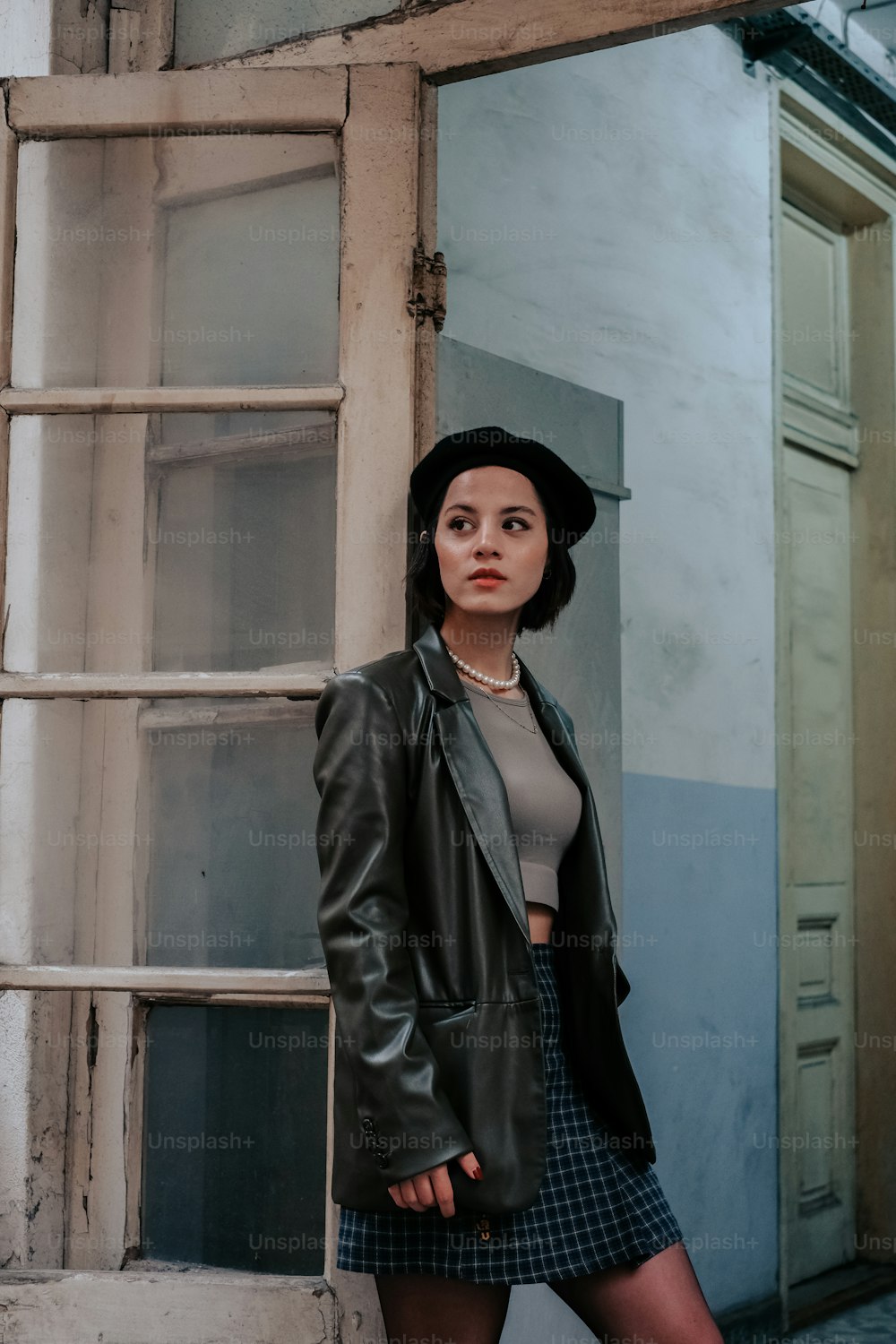 a woman leaning against a wall with a hat on