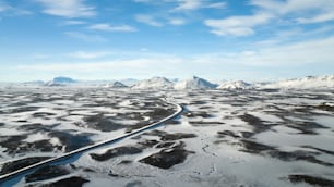 an aerial view of a snowy landscape with mountains in the background