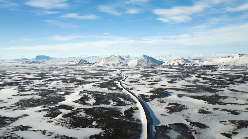 an aerial view of a snowy landscape with mountains in the background