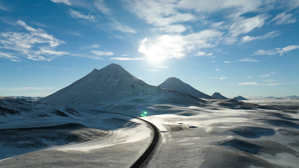uma montanha coberta de neve com um trilho de trem que a atravessa