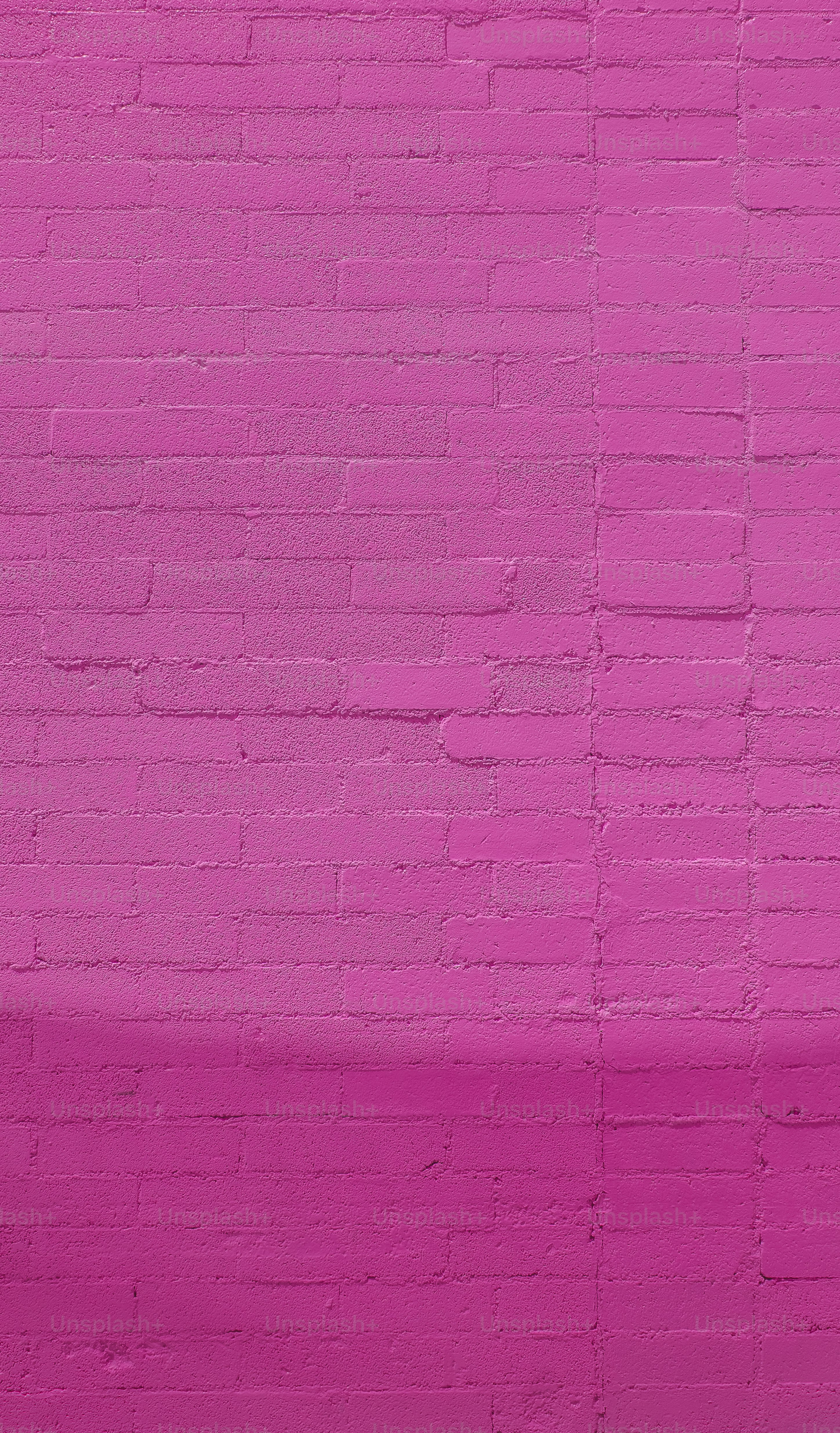 eine rosafarbene Ziegelmauer mit einer Bank davor