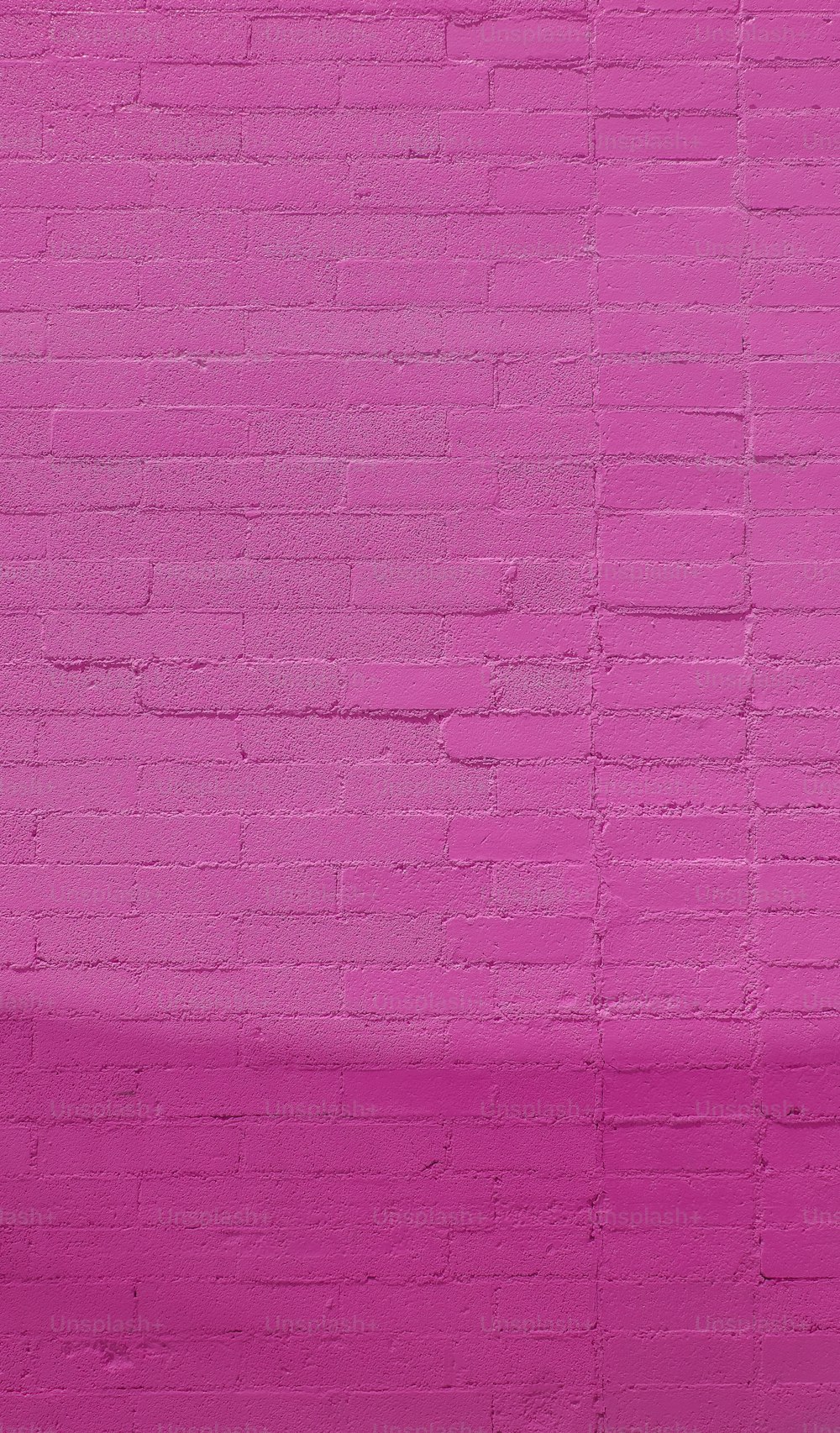 uma parede de tijolos rosa com um banco à sua frente