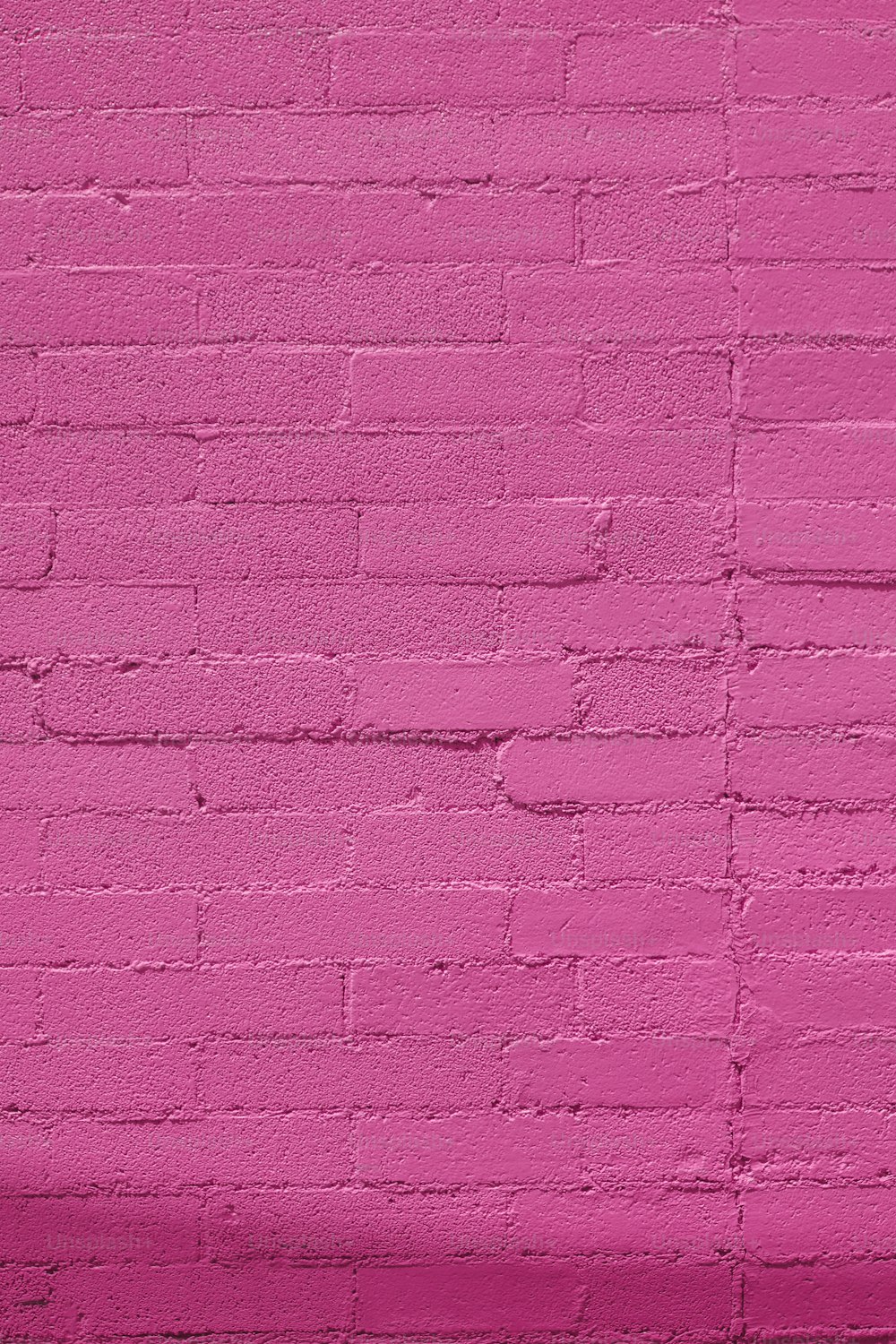 uma parede de tijolos rosa com um banco branco à sua frente