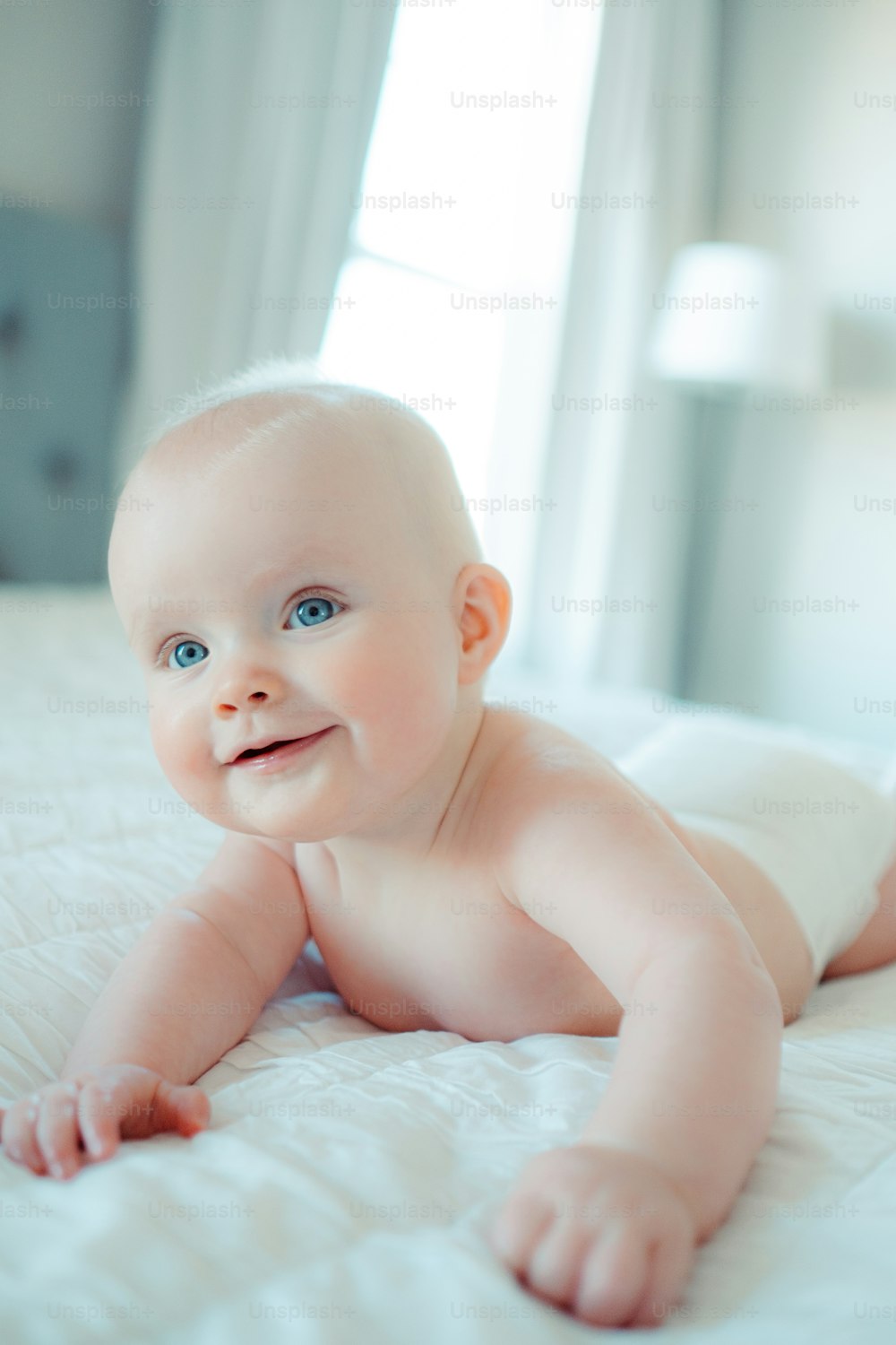 a smiling baby laying on a bed
