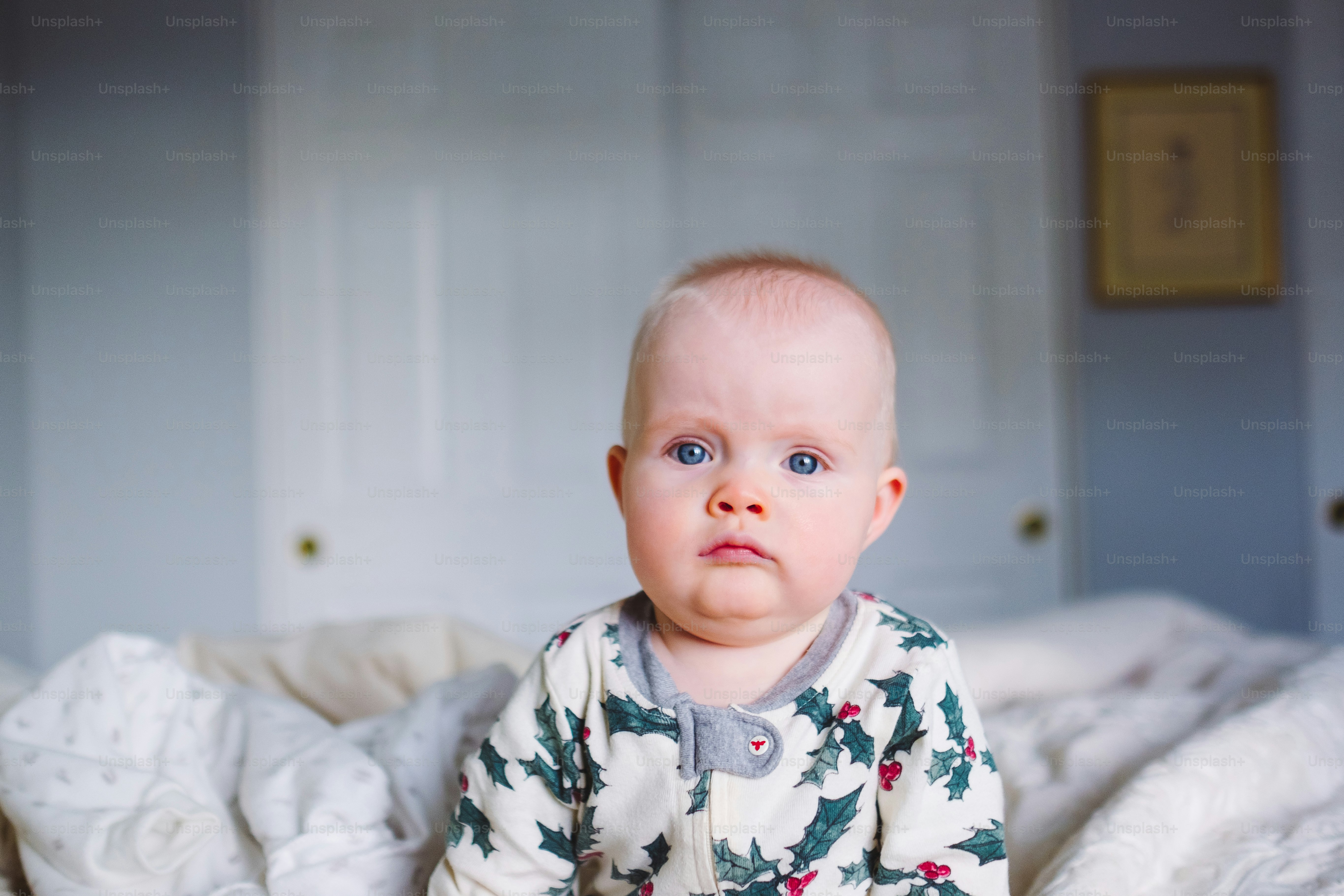 a baby sitting on a bed looking at the camera