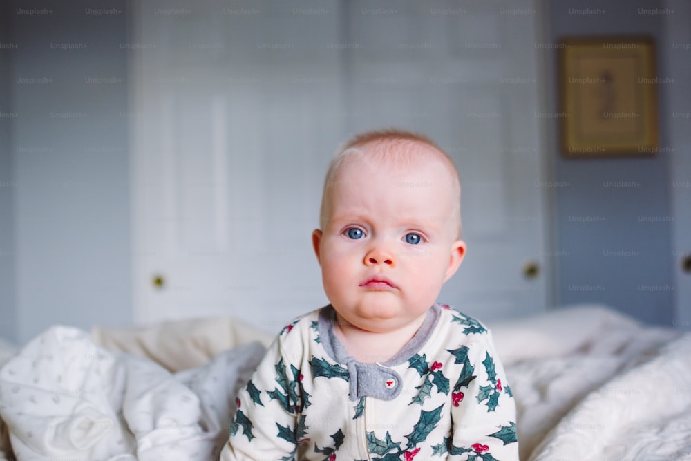 Ein Baby, das auf einem Bett sitzt und in die Kamera schaut