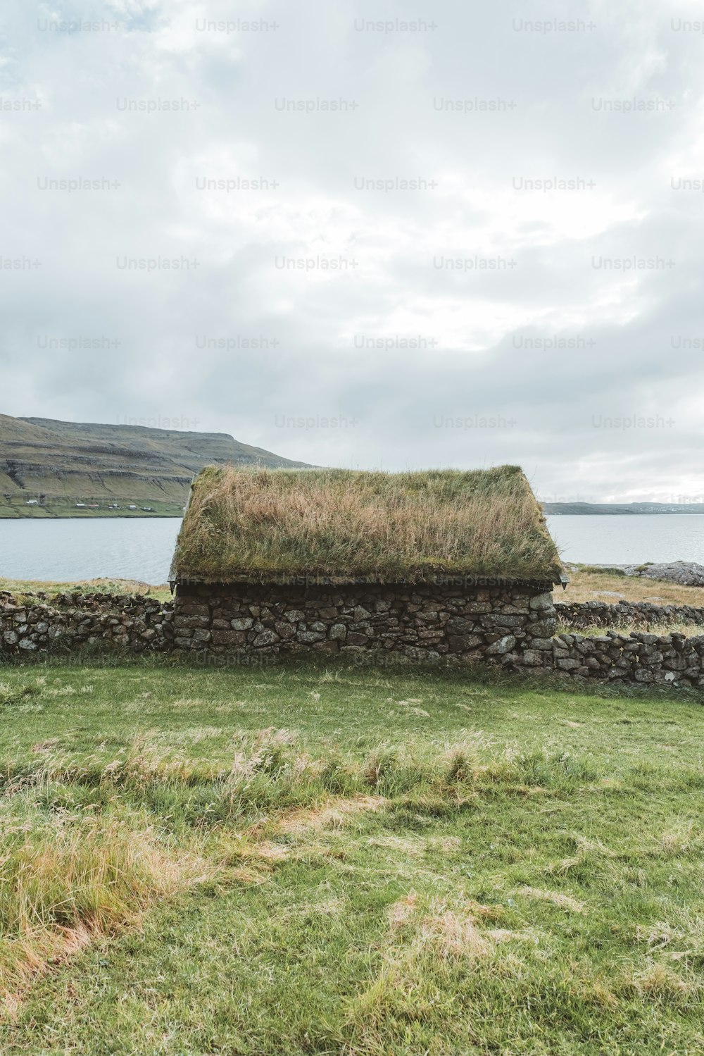 un mur de pierre avec un toit d’herbe à côté d’un plan d’eau