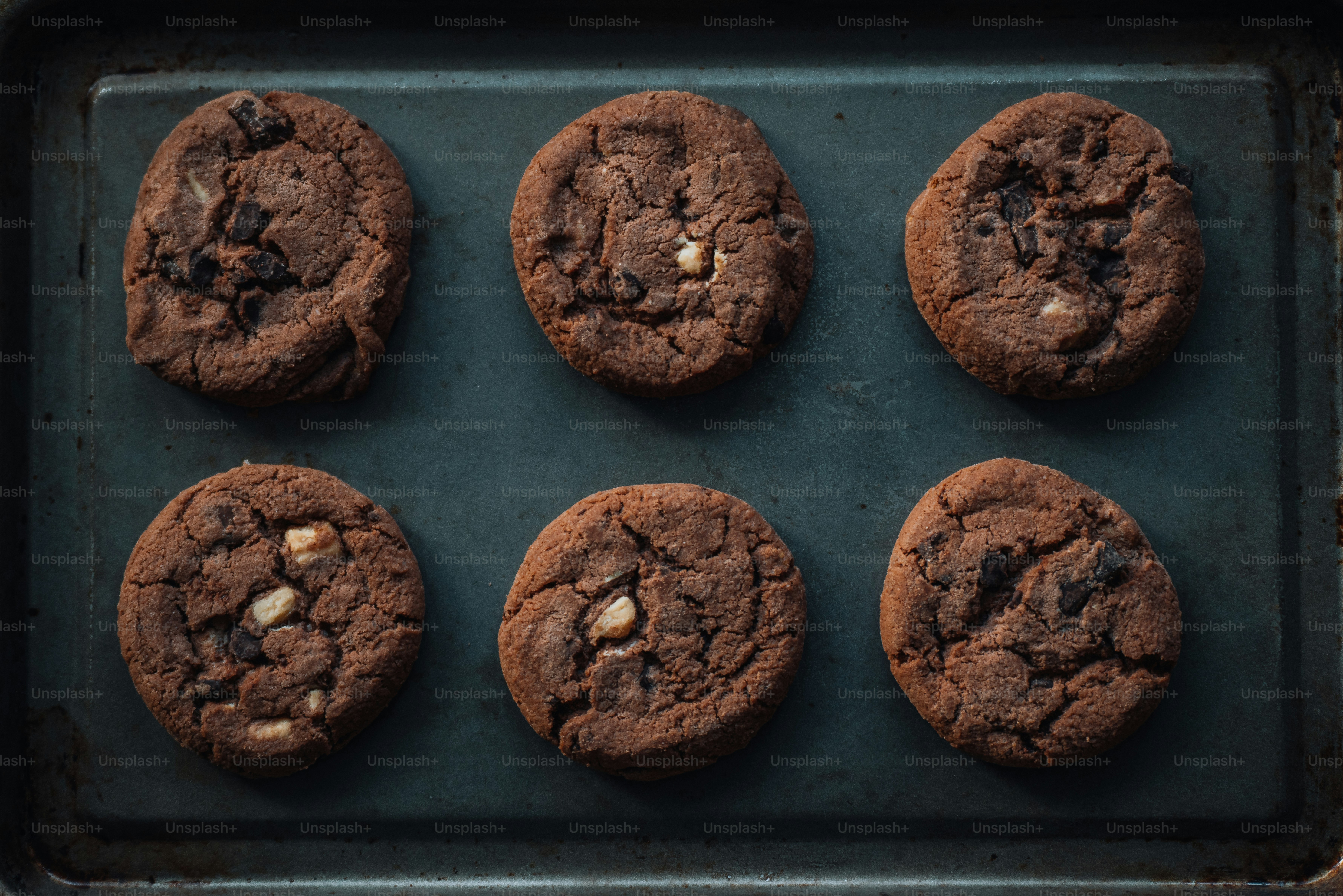 six chocolate chip cookies on a baking sheet