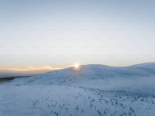 the sun is setting over a snowy mountain