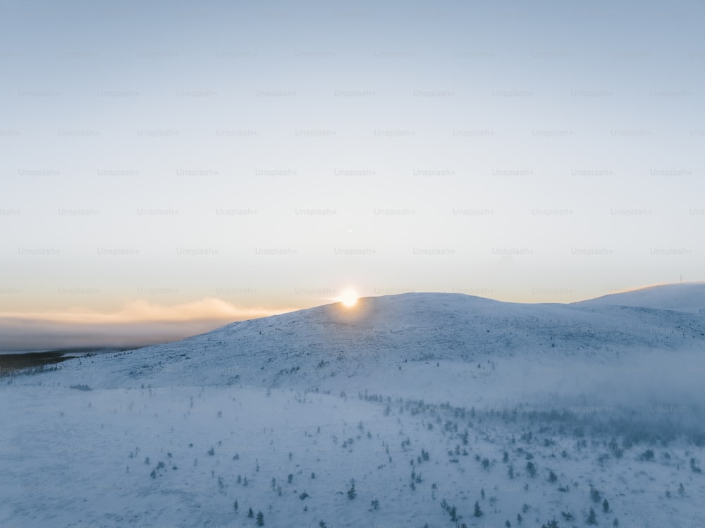 O sol está se pondo sobre uma montanha nevada