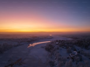 Die Sonne geht über einem zugefrorenen Fluss unter