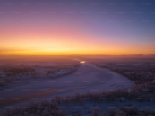 Die Sonne geht über einem zugefrorenen Fluss unter