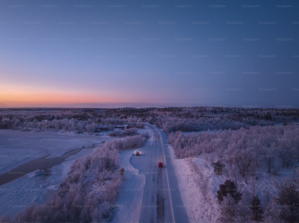 a car driving down a road in the middle of a snowy field