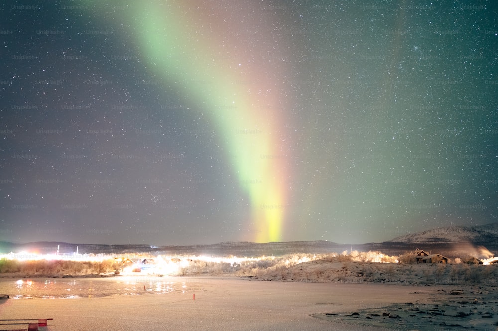 um arco-íris brilhante no céu sobre um campo coberto de neve