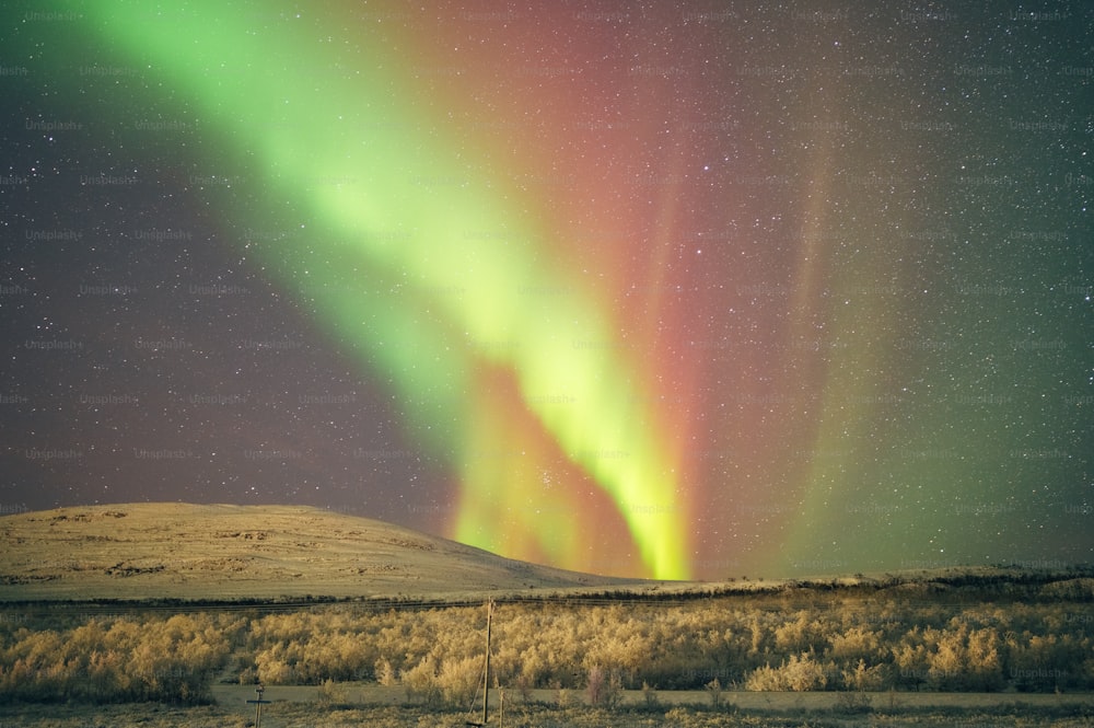 a green and red aurora bore in the night sky