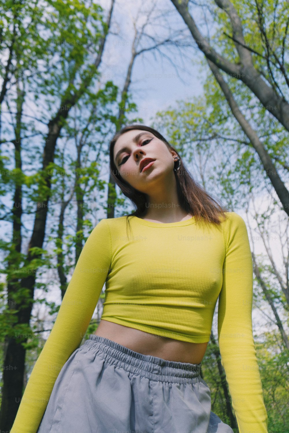 a woman in a yellow top standing in the woods