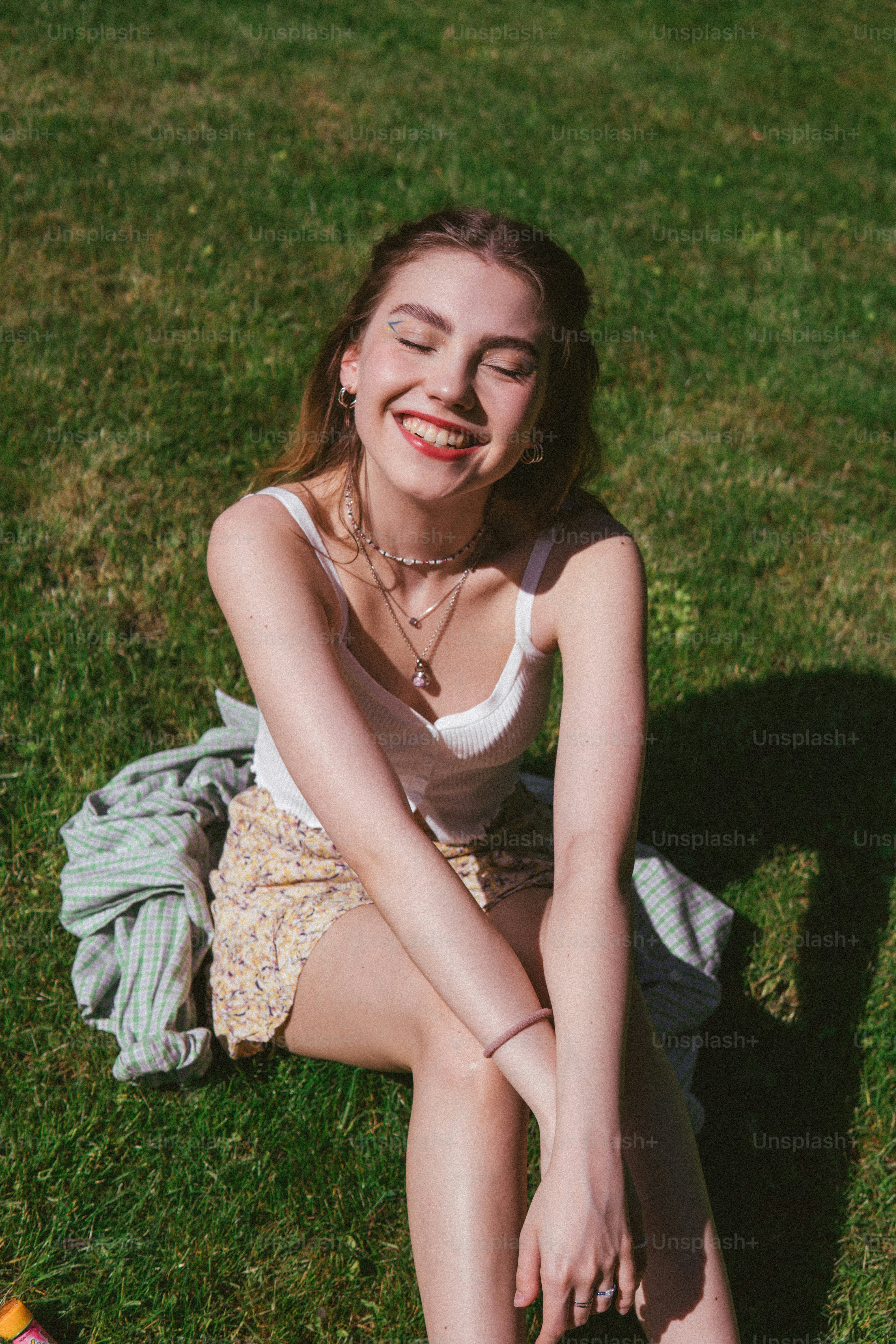 a woman sitting on the grass with her eyes closed