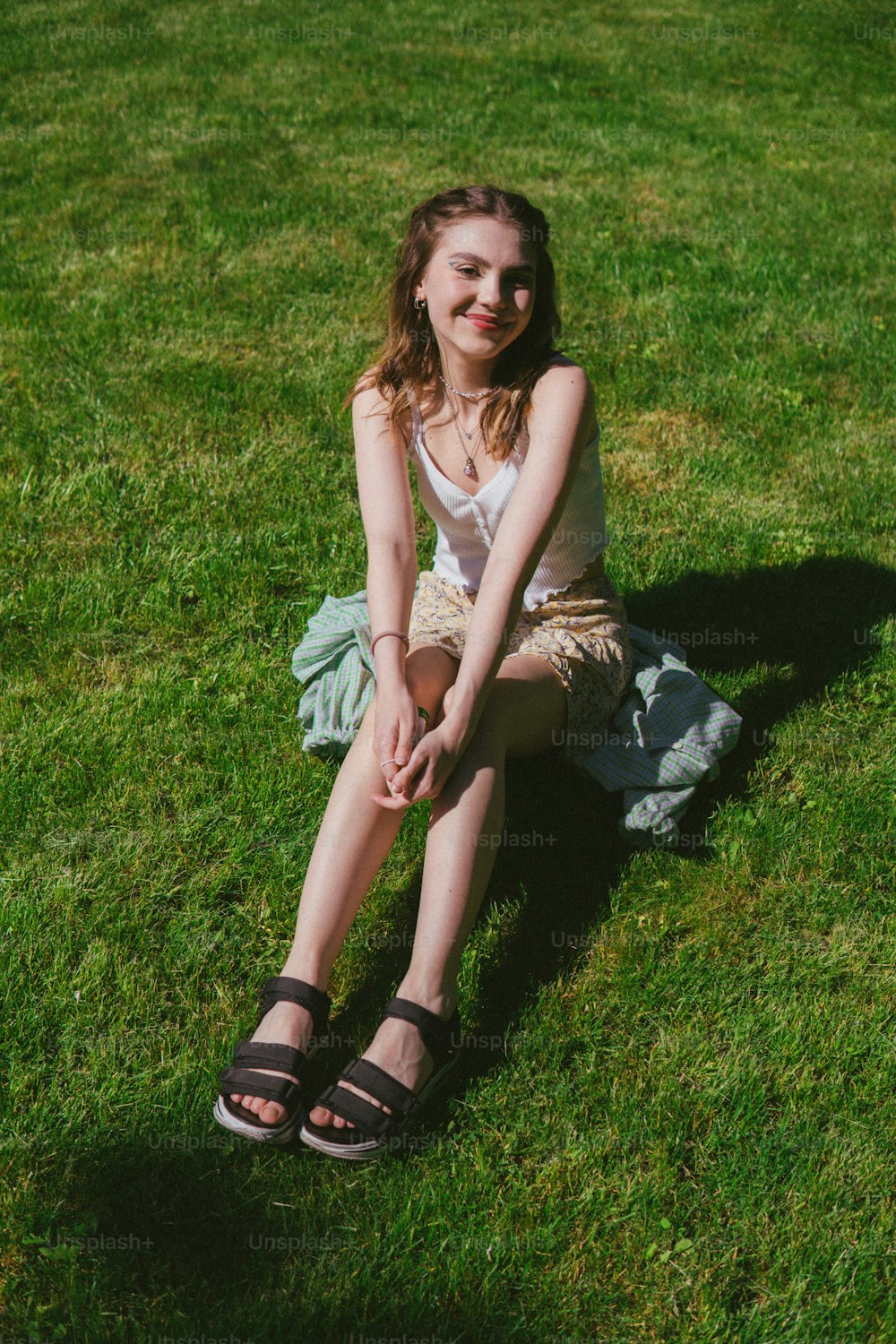 Una donna seduta sull'erba con le gambe incrociate
