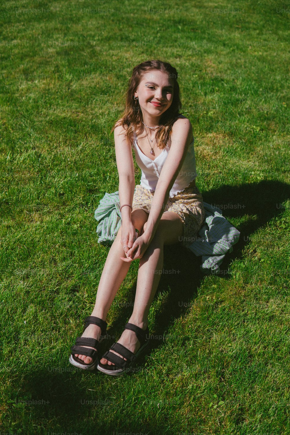 a woman sitting on the grass with her legs crossed