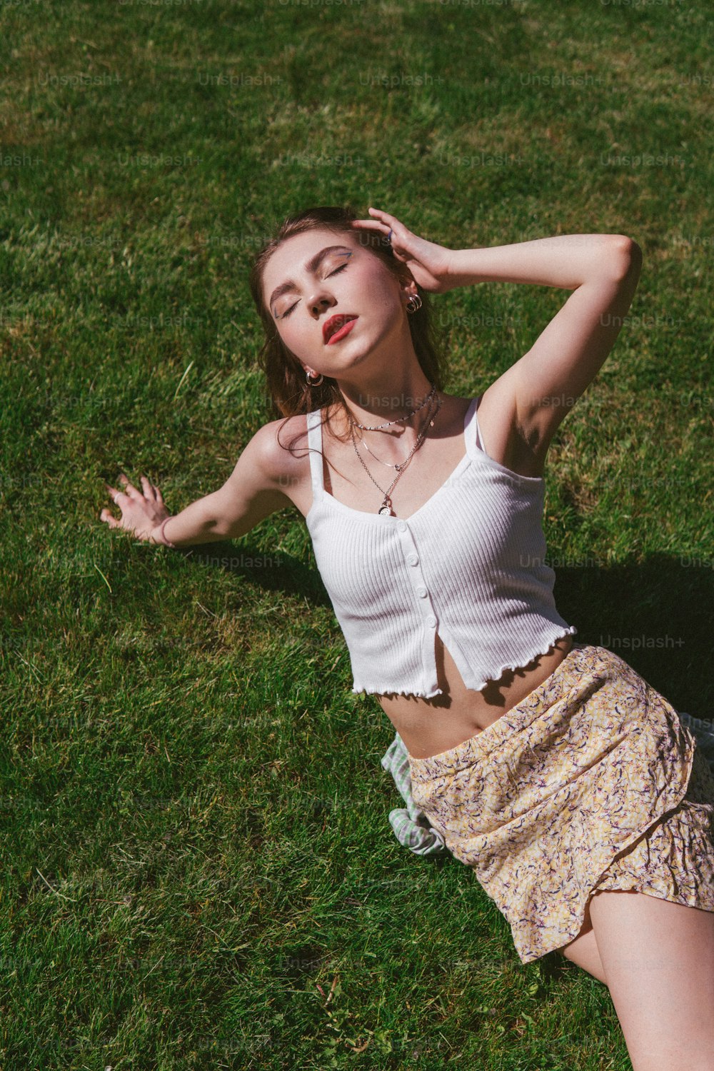 a woman laying in the grass with her hands behind her head