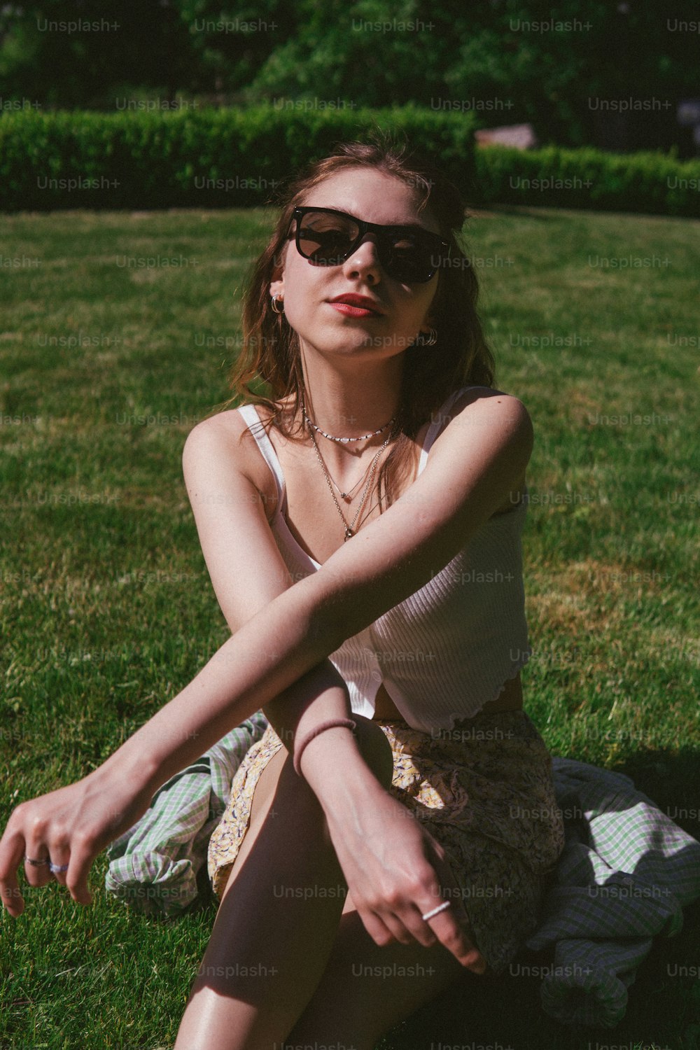 una donna seduta nell'erba che indossa occhiali da sole
